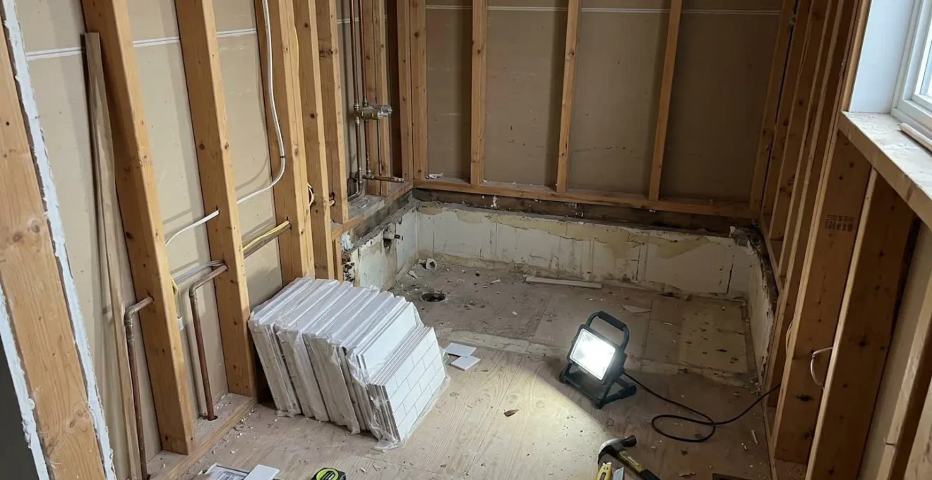 Salle de bain résidentielle en cours de rénovation avec murs dénudés exposant la charpente de bois et le sous-plancher